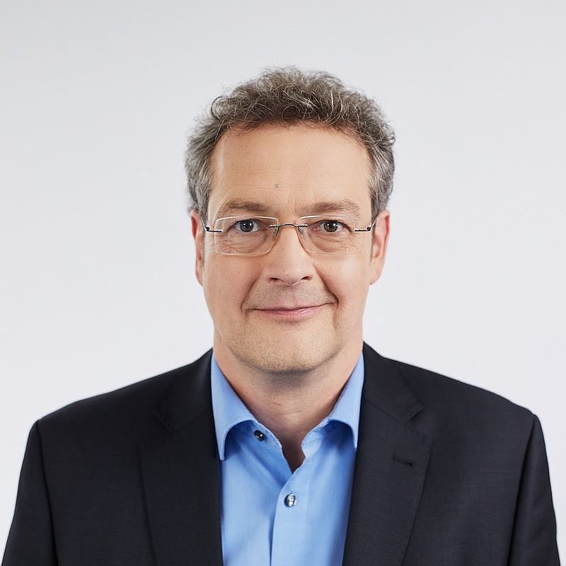 Portrait von Rainer Oberkötter im Anzug vor weißer Wand